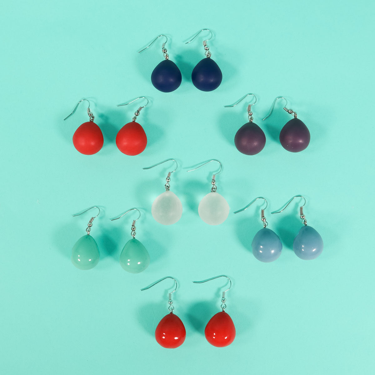 Multi coloured everyday drop earrings on a blue background.