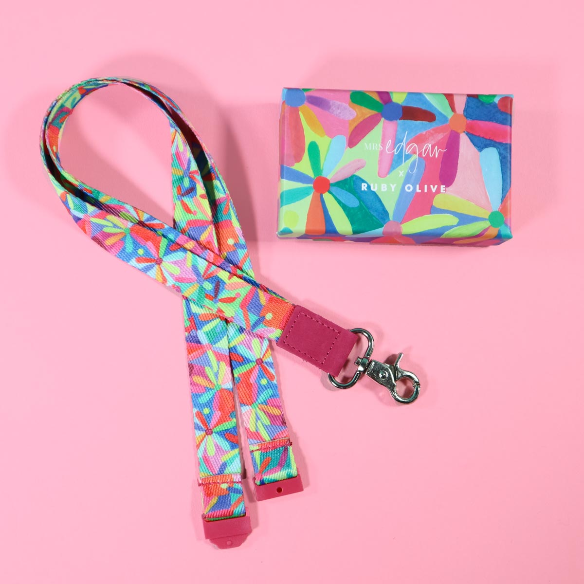 Colourful daisy patterned teachers lanyard with matching box on pink background.