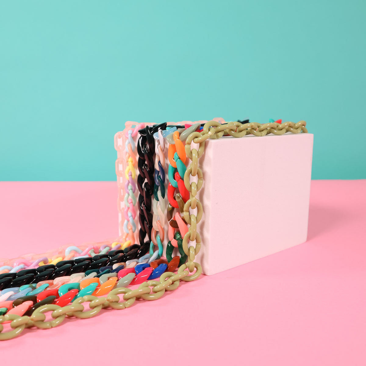 Colourful sunglass and mask chains on a pink and blue background.