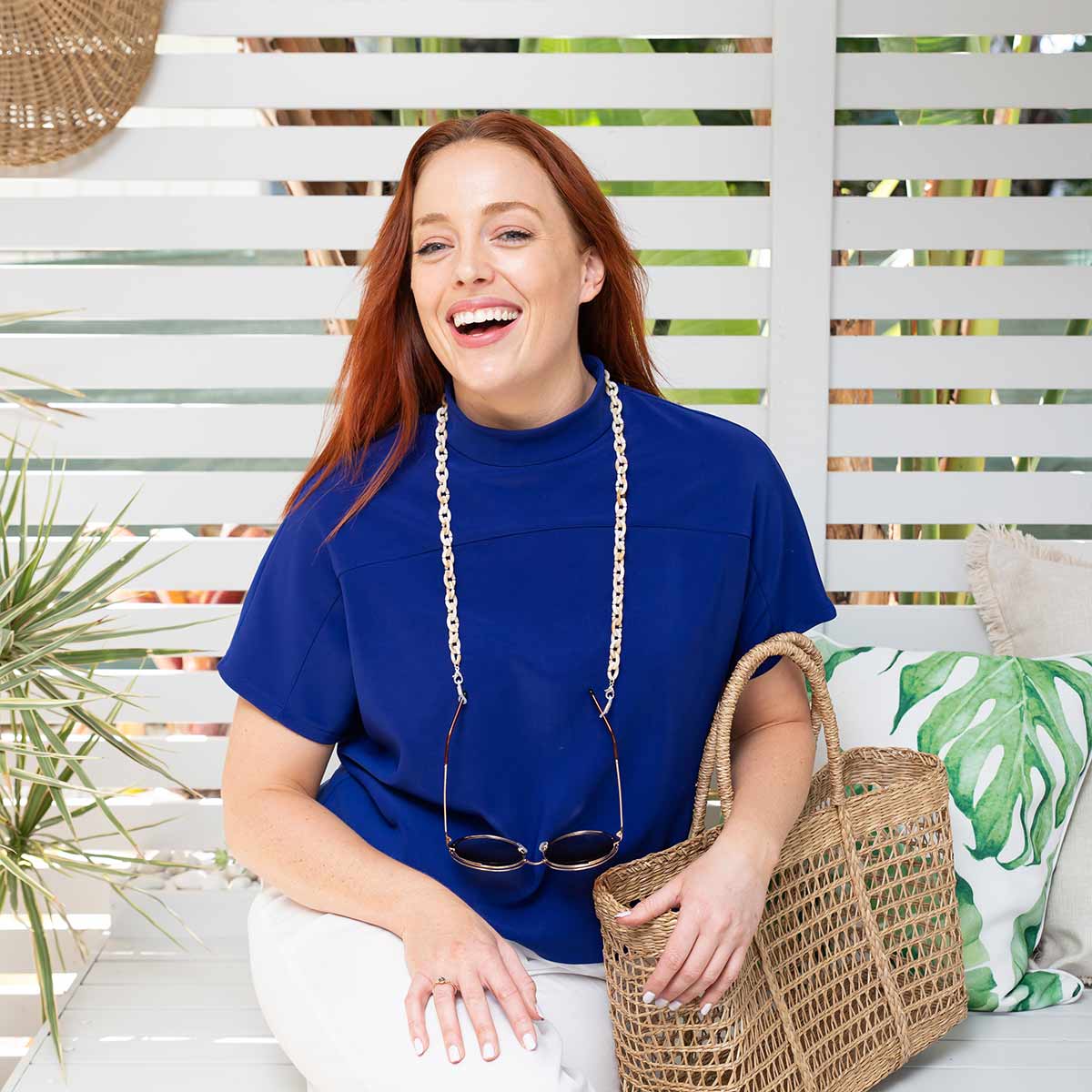 Smiling red headed women wearing glass chain with sunglasses.  