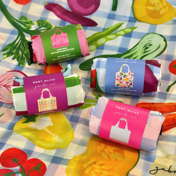 Four rolled up, bright, shopping bags on patterned fabric