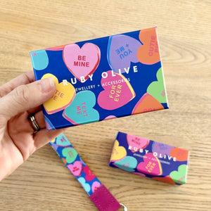 Colorful jewelry box with 'Ruby Olive' branding on a wooden surface