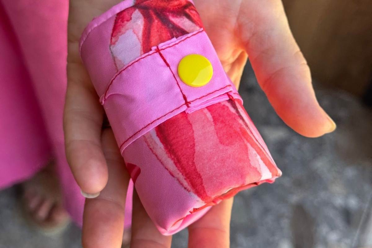 Pink fabric roll with a yellow button held by an adults hand.