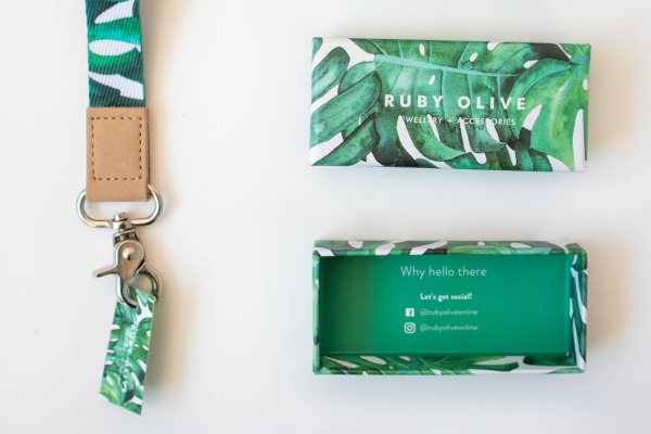 Green and white patterned lanyard with attached pouch and business card on a light background