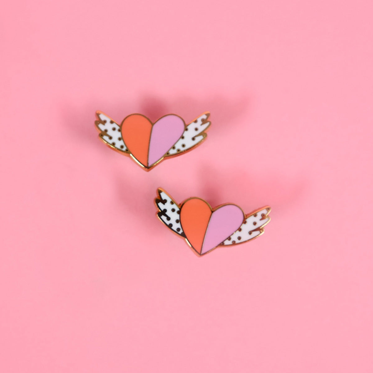 Flatlay of two toned winged heart shaped stud earrings.