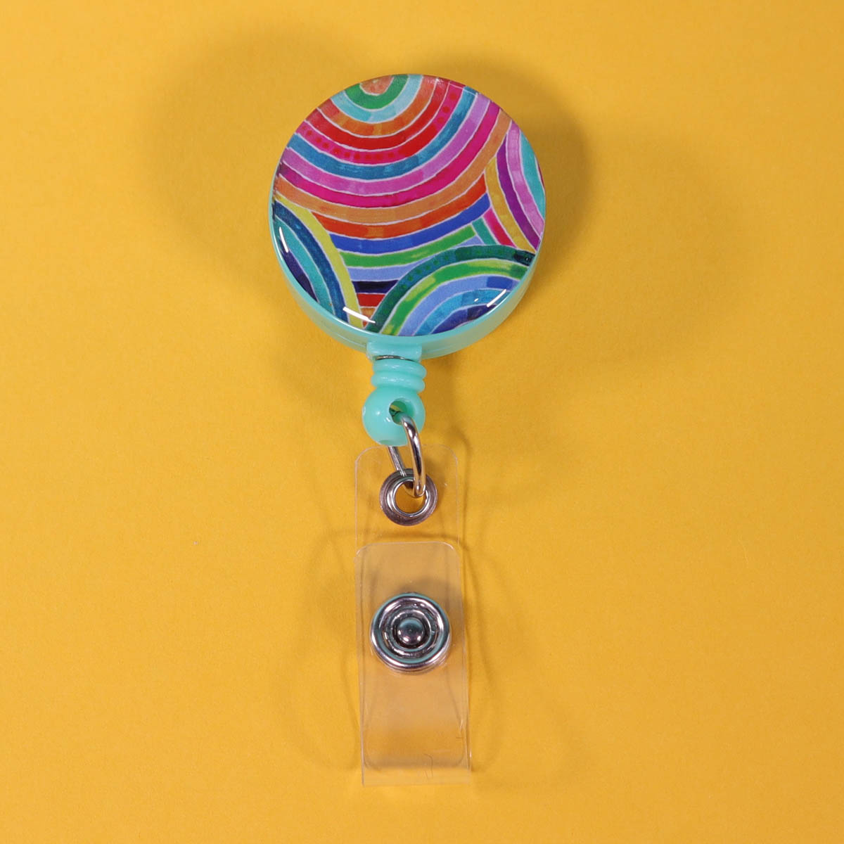Rainbow badge reel ID holder on a yellow background.