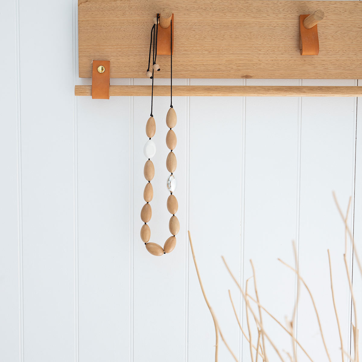 Hanging wood oval shaped pod necklace on a white background.