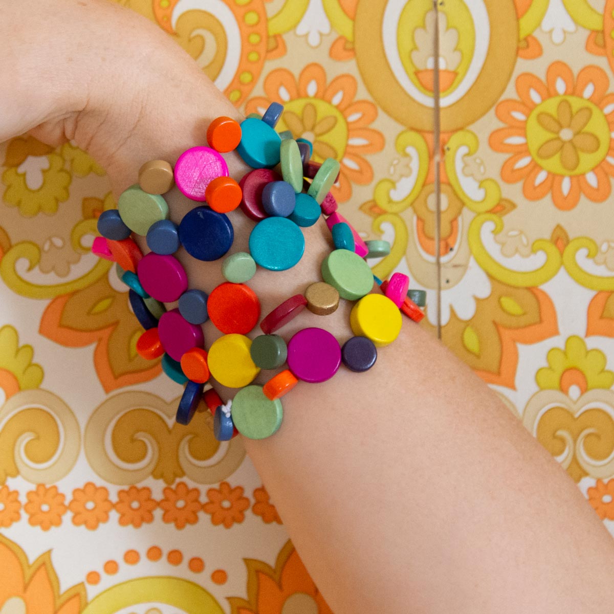 Bright and colourful bracelets on a wrist on a funky retro yellow background.
