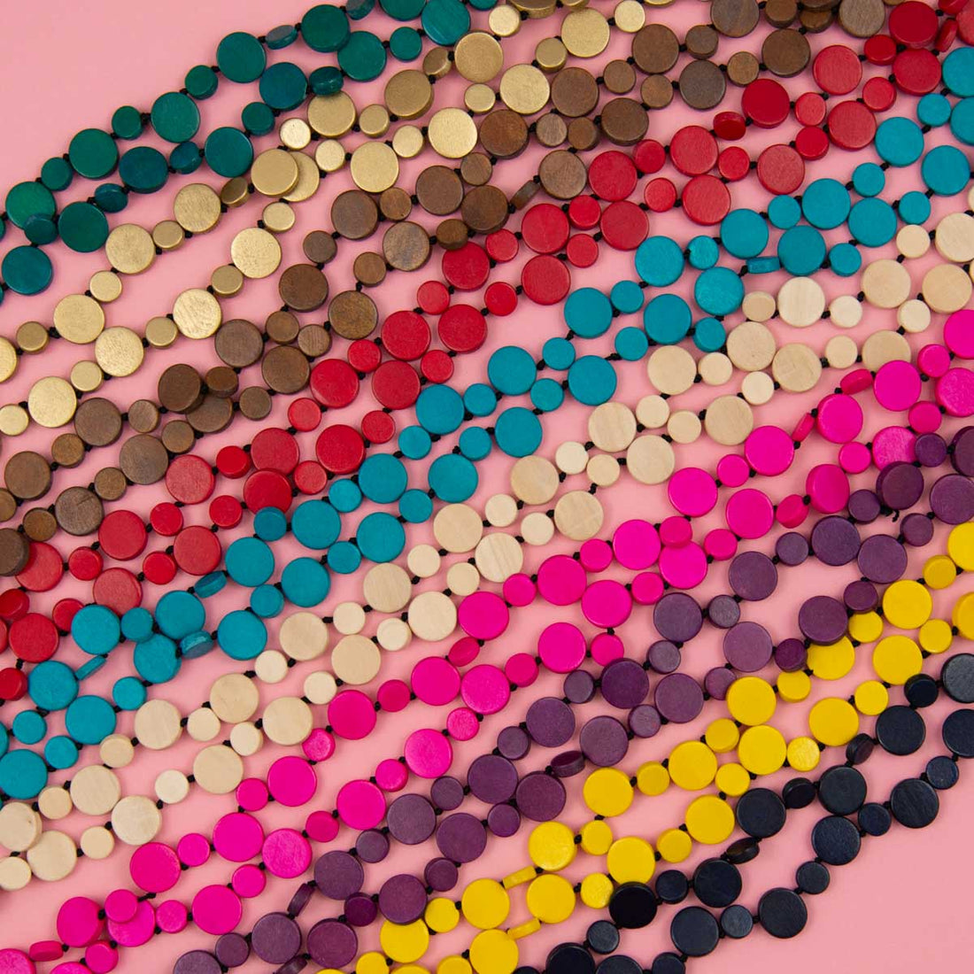Bright coloured single strand necklaces on pink background.