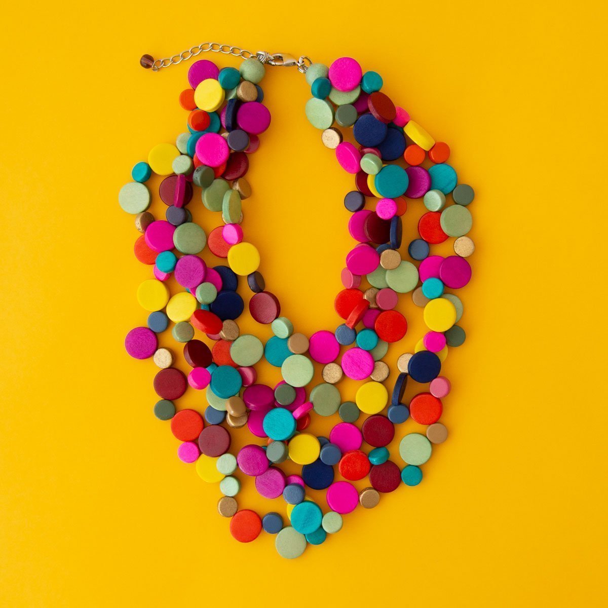 Bright multi coloured layered necklace on yellow background.