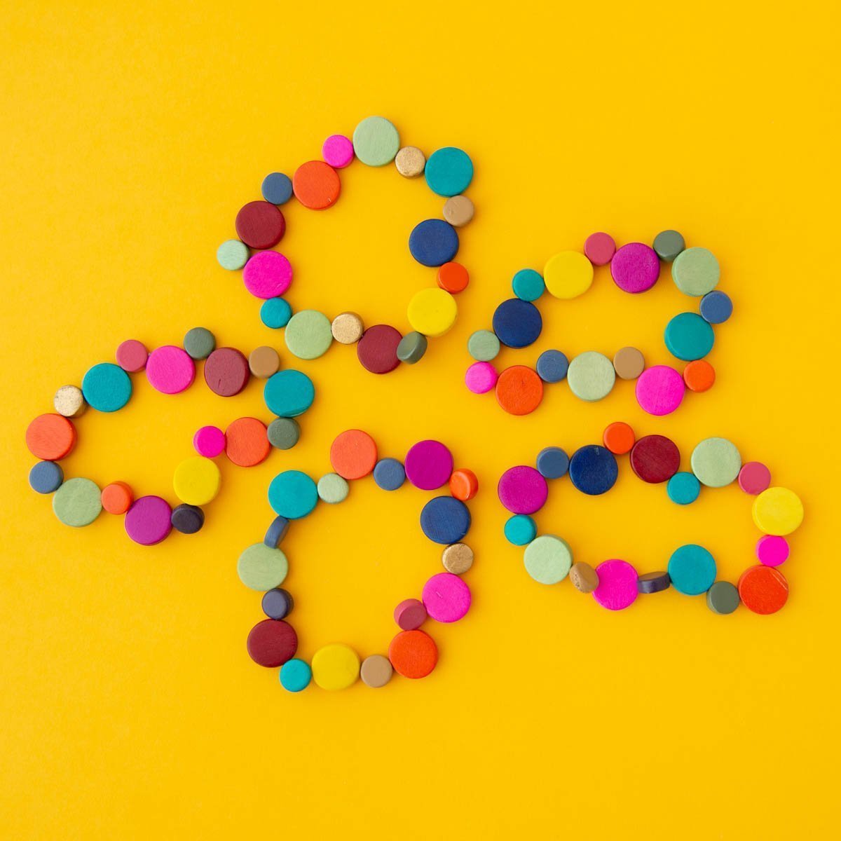 Five bright and colourful bracelets on a yellow background.