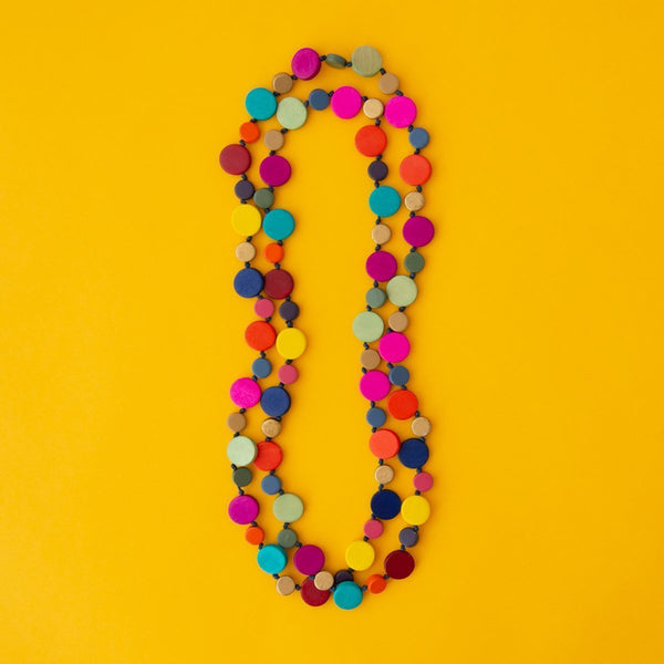 Long Rainbow coloured beaded necklace on yellow background.