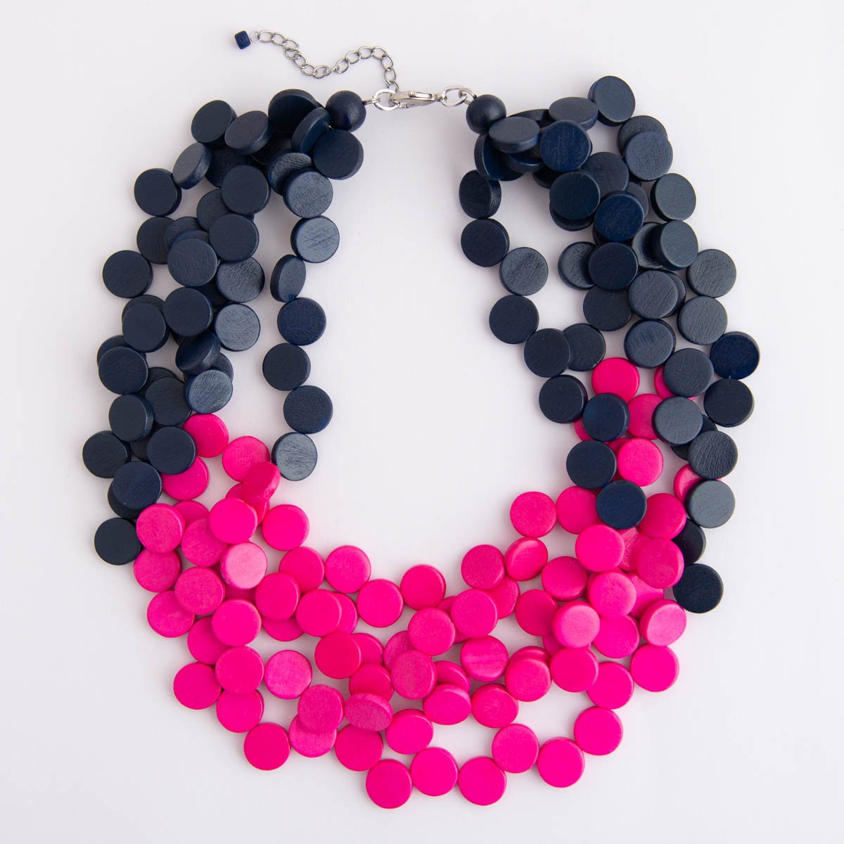 Bright pink and navy stacked wood beaded necklace on a white background.