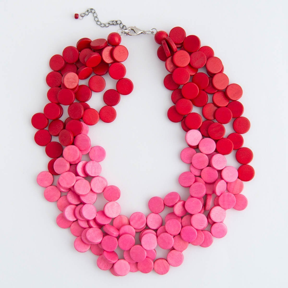 Bright pink and red stacked wood beaded necklace on a white background.