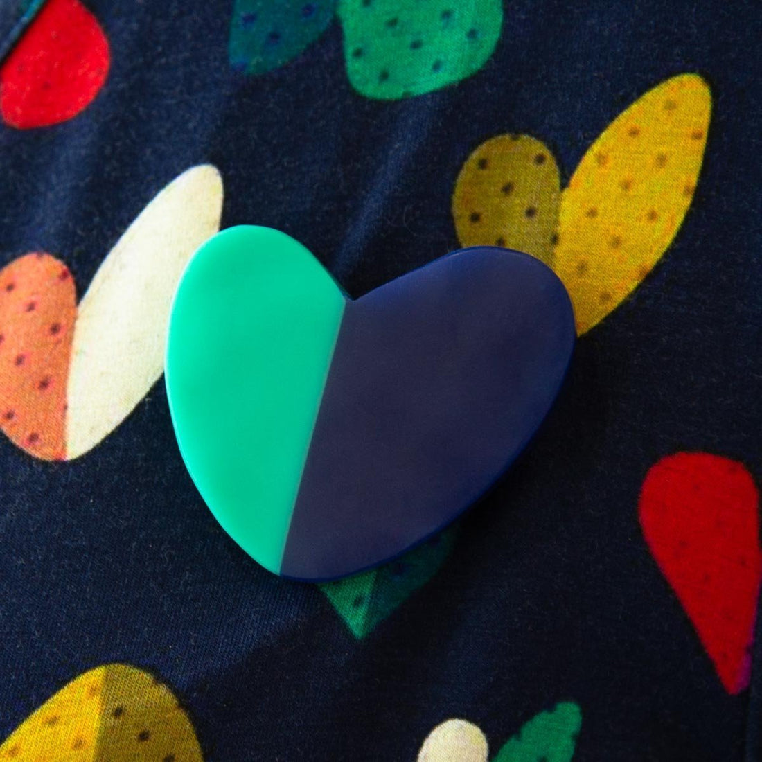 Aqua and navy heart shaped brooch on heart background.