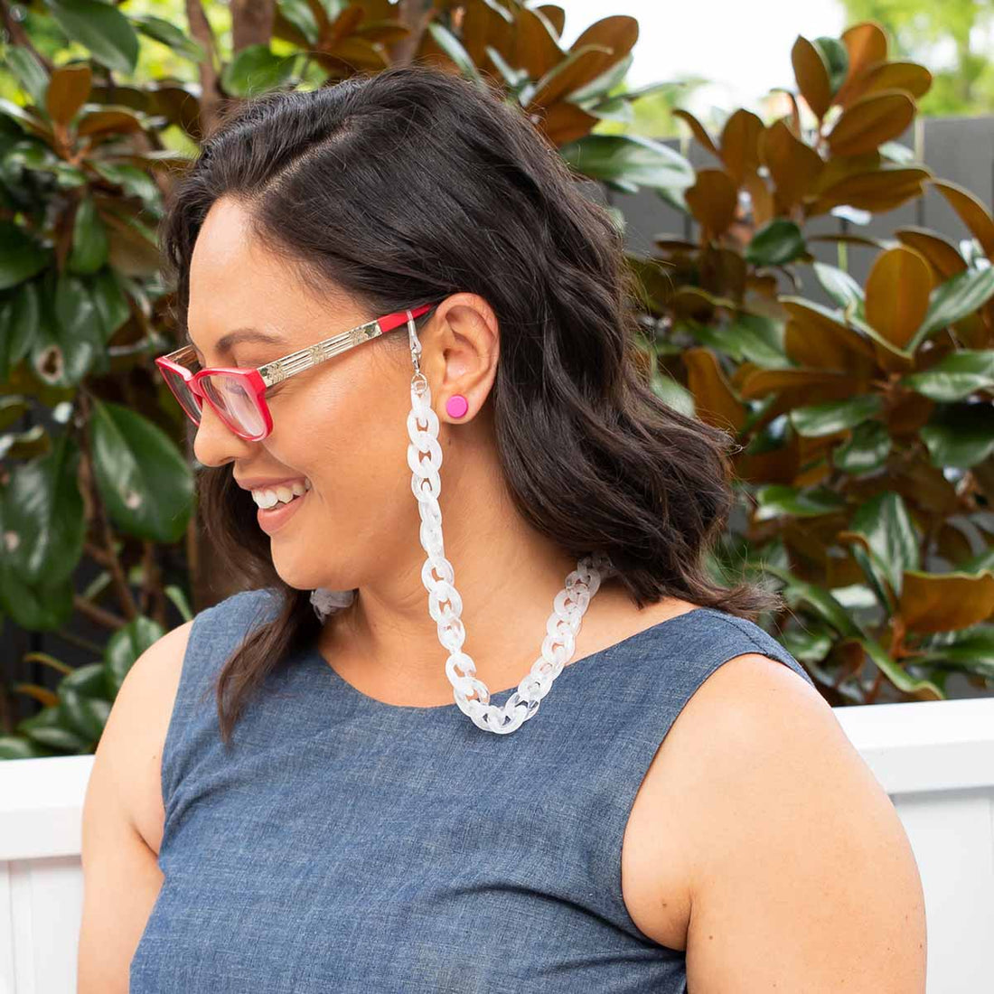 Smilling woman wearing frosted glasses chain and red glasses. 